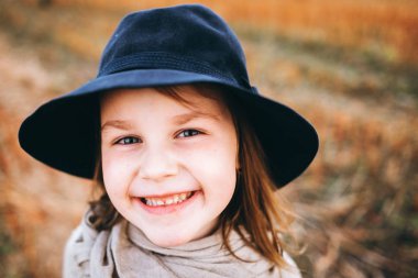 Gülümseyen kız panço ve şapka sonbahar alanı tarafından yürüyüş portresi