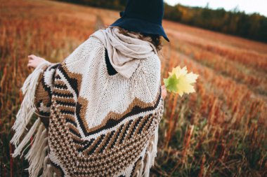 Sonbahar alanı tarafından yürümek poncho kızın arkadan görünüş