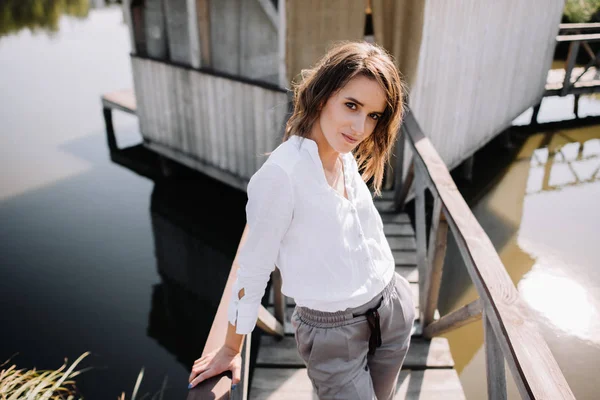 Stylish woman in casual clothes posing on wooden pier