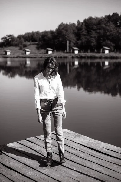 Stylish woman in casual clothes posing on wooden pier