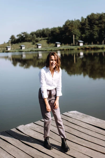 Stylish woman in casual clothes posing on wooden pier