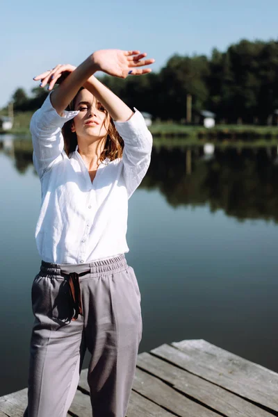 Stylish woman in casual clothes posing on wooden pier