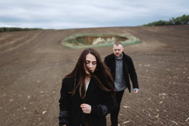 Üzgün kadın ve adam tarlada yürüyor.