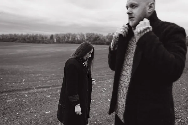 Black and white photo of sad couple posing on field