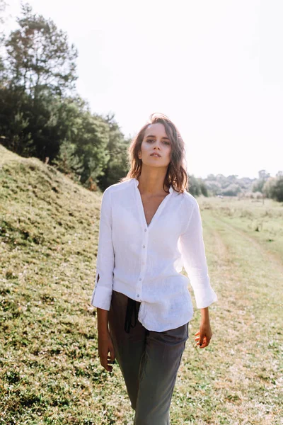 Woman in casual outfit posing in field in bright sunlight