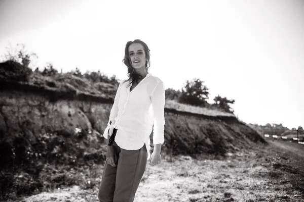 Black and white photo of woman in shirt and pants posing in field