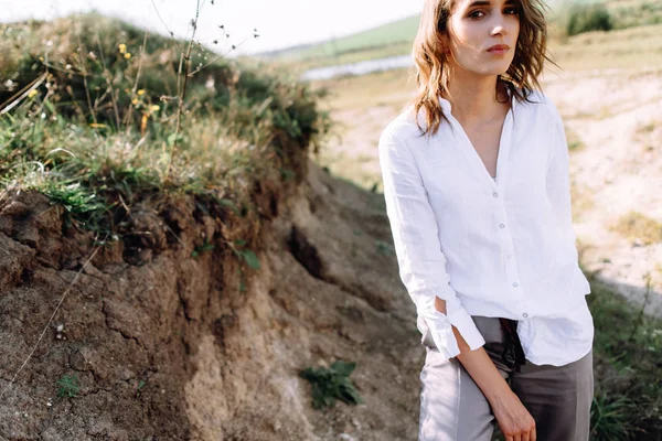 Portrait of woman in shirt and pants posing on hills background