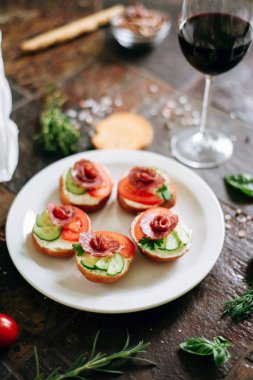 Philadelphia peynir, salam, salatalık ve domates ile bruschettas kırmızı şarap ile servis.