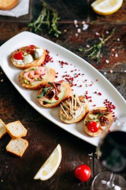 Beyaz Oval plaka üzerinde farklı Topingler ile bruschettalar seti