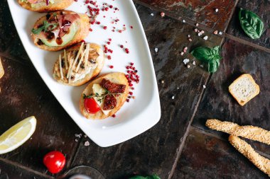 Beyaz Oval plaka üzerinde farklı Topingler ile bruschettalar seti