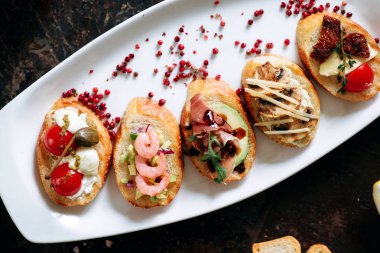 Beyaz Oval plaka üzerinde farklı Topingler ile bruschettalar seti