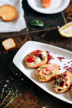 Beyaz Oval plaka üzerinde farklı Topingler ile bruschettalar seti