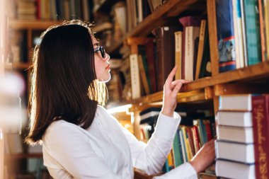 Kütüphanede kitap seçme genç kız