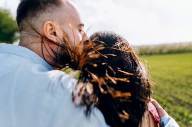 Yakın plan öpüşme portresi. Bahar tarlasında aşk hikayesi. Sevgi dolu çift sarılıyor ve yürüyor. 