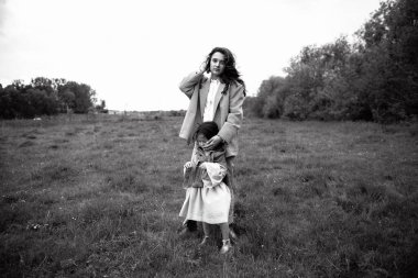 Anne ve kızı birlikte zaman geçirir, çimlerin üzerinde yürürler..