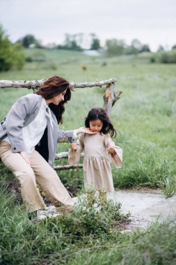 Ormanın yakınındaki bir yaya köprüsünde kızıyla birlikte anne portresi.