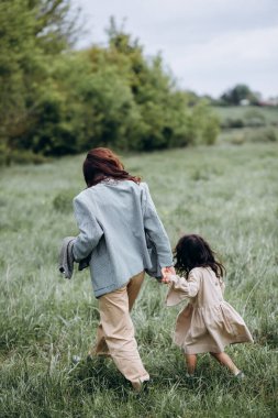 Anne ve kızı birlikte zaman geçirir, çimlerin üzerinde yürürler..