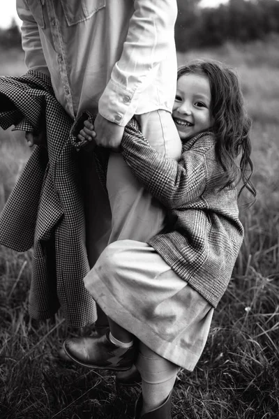 Tarz sahibi anne ve kız yağmur yağdığında nehir kenarındaki yeşil çimlerin olduğu bir arazide eğleniyorlar.