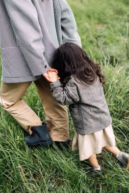 Anne ve kızı yeşil alanda birlikte eğleniyorlar. Gülümseyen anne güzel kızının elini tutuyor.. 