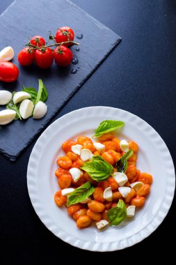 Patates gnocchi alla Sorrentina domates soslu Yeşil taze fesleğen ve mozzarella topları ile bir tabakta