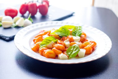Gnocchi domates soslu Yeşil taze fesleğen ve mozzarella topları ile bir tabakta. İtalyan tarifi
