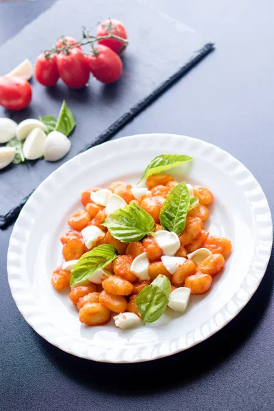 Patates gnocchi alla Sorrentina domates soslu Yeşil taze fesleğen ve mozzarella topları ile bir tabakta