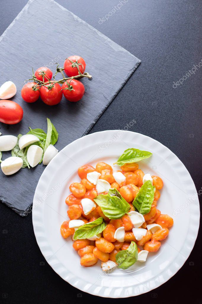 Potato gnocchi alla Sorrentina in tomato sauce with green fresh basil and mozzarella balls served on a plate