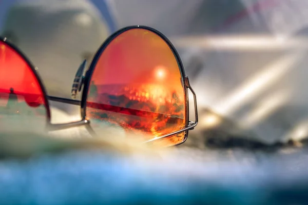 Occhiali da sole con riflesso di spiaggia estiva con sabbia nera, sole e mare. Capri Italia Immagine Stock