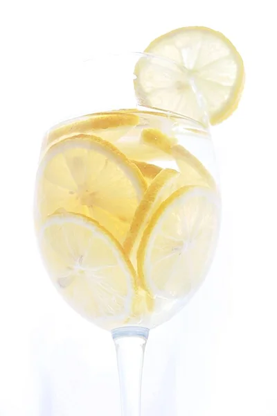 Δροσιστικό λεμονάδα ή λιμοντσέλο κρύο ποτό. Κομμένα φρέσκα ώριμα λεμόνια σε διάφανο ποτήρι — Φωτογραφία Αρχείου
