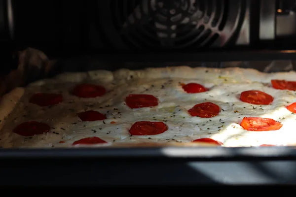 Roher Focaccia-Teig mit geschnittenen frischen Tomaten Kirsche auf einem Backblech. — Stockfoto