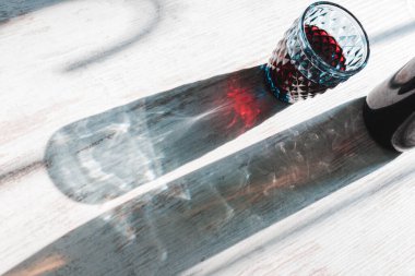 Işıl ışıl parlayan uzun gölgeler ve kristal mavi şarap kadehi ve şişe optik etkisi..