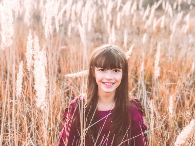 Autumn 'da eğleniyorum. Ilık Sonbahar doğal fotoğrafı. Mavi kazak giyen, gülümseyen genç bir kız. Turuncu ve sarı çivili.