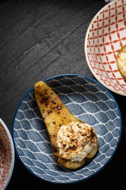 Süzme peynirle doldurulmuş fırında armut ya da tarçınlı güveç koyu arka planda renkli kâselerde, yukarıdan yazı için boşluk ile görülür..