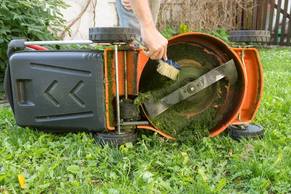Людина прибирає газонокосарку — стокове фото