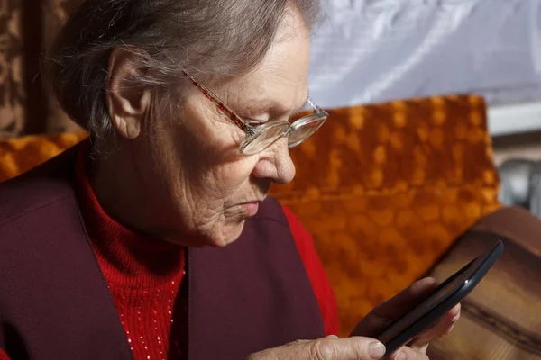非常に古いです女性読みます電子書籍リーダー座っています彼女のソファ — ストック写真