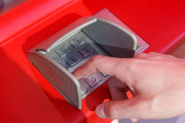 hand entering pin code at cash machine