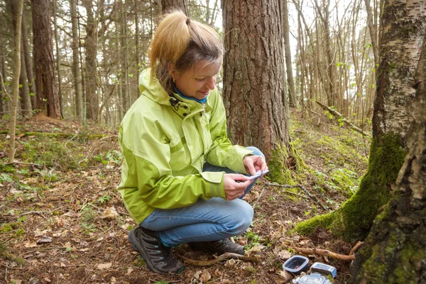 Eine Frau beim Geocaching. Frauen im Wald finden Geocache. — Stockfoto