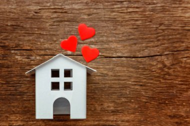 Rustik eski vintage ahşap arka plan üzerinde üç kırmızı kalpler ile minyatür beyaz oyuncak evi. Mortgage Emlak sigorta rüya ev concept