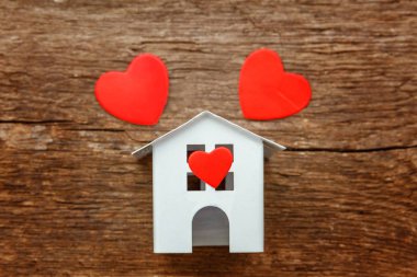 Rustik eski vintage ahşap arka plan üzerinde üç kırmızı kalpler ile minyatür beyaz oyuncak evi. Mortgage Emlak sigorta rüya ev concept