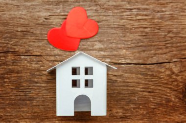 Rustik eski vintage ahşap arka plan üzerinde iki kırmızı kalp ile minyatür beyaz oyuncak ev. 