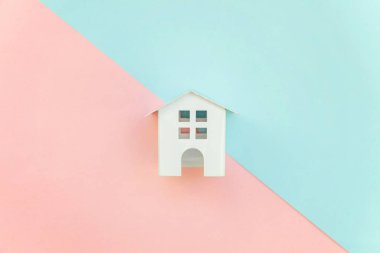 Pembe ve mavi pastel renk kağıt geometrik düz yatıyordu arka plan minyatür beyaz oyuncak ev. Mortgage Emlak sigorta rüya ev concept