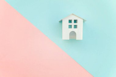 Pembe ve mavi pastel renk kağıt geometrik düz yatıyordu arka plan minyatür beyaz oyuncak ev. Mortgage Emlak sigorta rüya ev concept