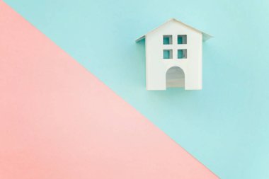 Pembe ve mavi pastel renk kağıt geometrik düz yatıyordu arka plan minyatür beyaz oyuncak ev. Mortgage Emlak sigorta rüya ev concept