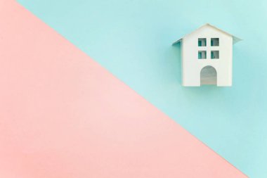 Pembe ve mavi pastel renk kağıt geometrik düz yatıyordu arka plan minyatür beyaz oyuncak ev. Mortgage Emlak sigorta rüya ev concept