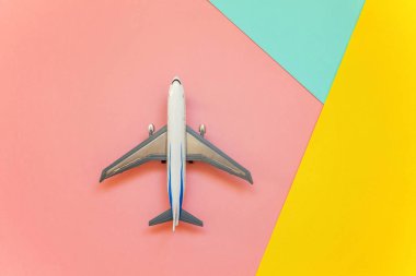 Minyatür oyuncak model uçak mavi, sarı ve pembe pastel renkli kağıt geometrik arka plan üzerinde sadece düz yatıyordu tasarım. Uçak tatil yaz hafta sonu deniz macera seyahat kavramı ile seyahat