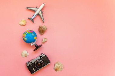 Düz Lay oyuncak uçak, vintage film fotoğraf makinesi, küre ve kabuk üzerinde pembe renkli pastel trendy modern moda arka plan ile. Tatil seyahat yaz hafta sonu deniz macera seyahat kavramı