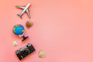 Düz Lay oyuncak uçak, vintage film fotoğraf makinesi, küre ve kabuk üzerinde pembe renkli pastel trendy modern moda arka plan ile. Tatil seyahat yaz hafta sonu deniz macera seyahat kavramı