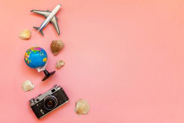 Düz Lay oyuncak uçak, vintage film fotoğraf makinesi, küre ve kabuk üzerinde pembe renkli pastel trendy modern moda arka plan ile. Tatil seyahat yaz hafta sonu deniz macera seyahat kavramı