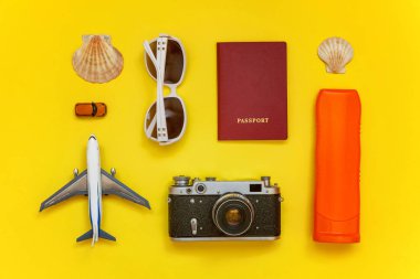 Güneş kremi, çınar, bağbozumu kamera, pasaport, güneş gözlüğü ve kabuk üzerinde sarı renkli şık modern moda arka plan ile düz yatıyordu. Tatil seyahat yaz hafta sonu deniz macera seyahat kavramı