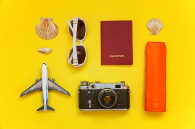 Güneş kremi, çınar, bağbozumu kamera, pasaport, güneş gözlüğü ve kabuk üzerinde sarı renkli şık modern moda arka plan ile düz yatıyordu. Tatil seyahat yaz hafta sonu deniz macera seyahat kavramı